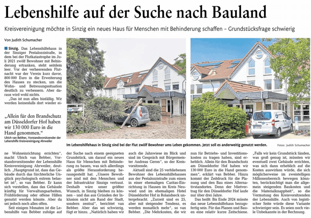 Ein zweistöckiges Haus mit rotem Ziegeldach ist abgebildet, vor dem ein Mann mit einer Rollstuhlrampe steht.