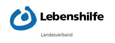 Blaues abstraktes Logo, das einer Person in einem Kreis ähnelt, neben dem fettgedruckten schwarzen Text „Lebenshilfe“. Darunter steht in kleinerem grünen Text „Landesverband“ auf weißem Hintergrund.