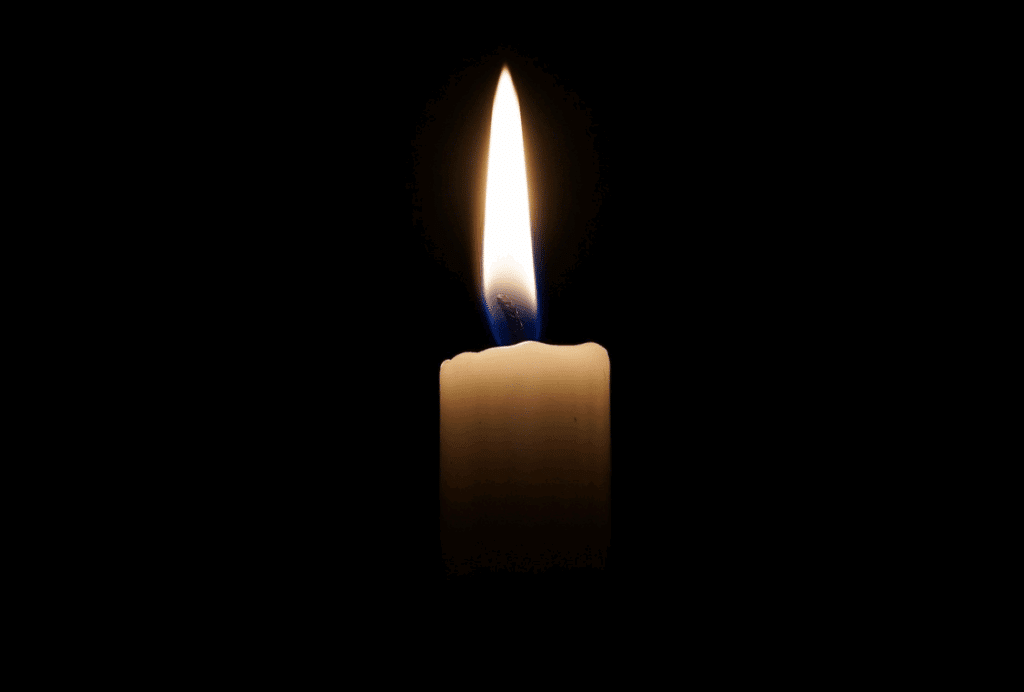 Eine einzelne brennende Kerze leuchtet in der Dunkelheit mit einer kleinen, gleichmäßigen Flamme.